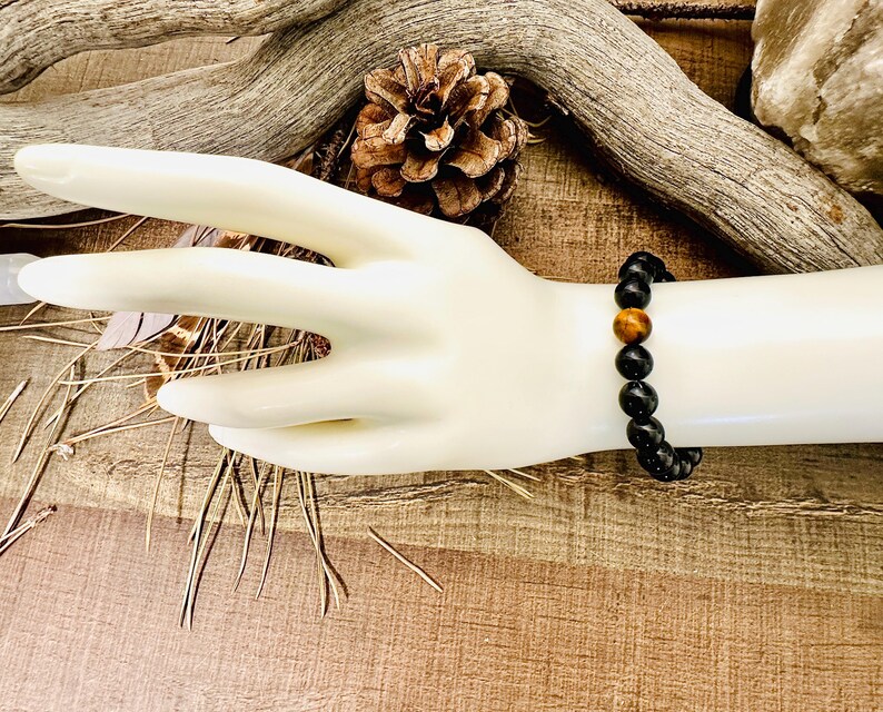 May include: A black beaded bracelet with a single tiger's eye bead.