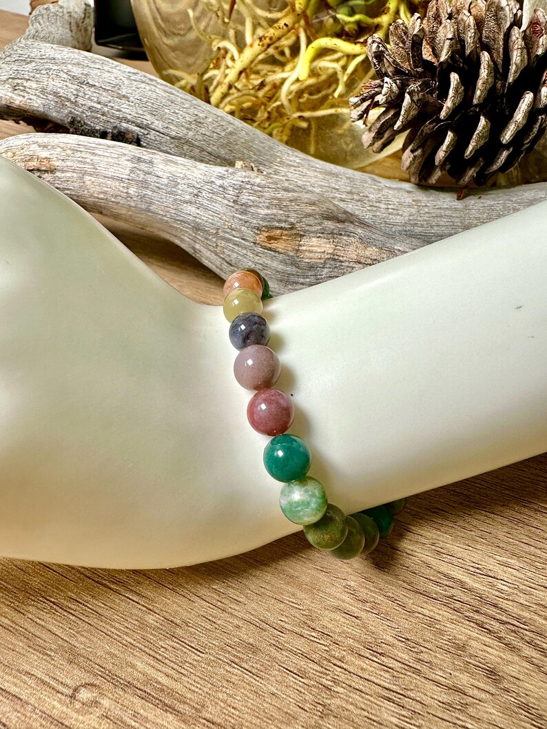 May include: A multi-colored gemstone bracelet with round beads in shades of green, pink, yellow, and blue.