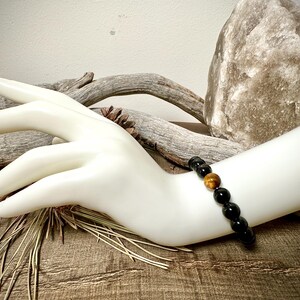 May include: A black and gold beaded bracelet with tiger's eye beads.