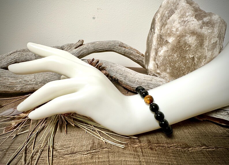 May include: A black and gold beaded bracelet with tiger's eye beads.