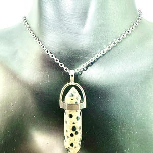 May include: A silver chain necklace with a dalmatian jasper pendant. The pendant is a point with a silver cap and a silver bail.