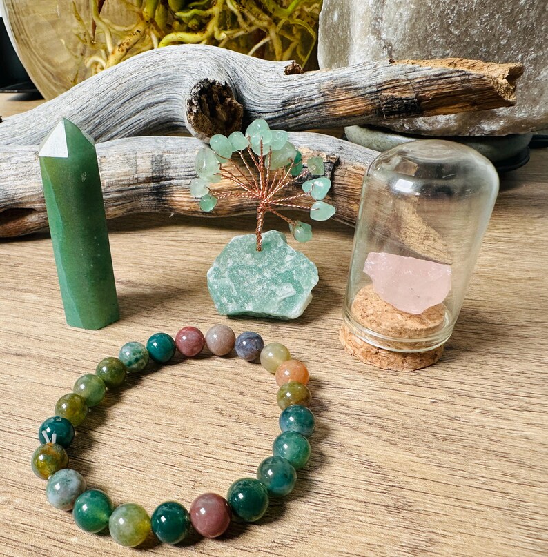 May include: A green agate crystal point, a green agate tree, a green agate bracelet, and a pink rose quartz in a glass jar with a cork lid.