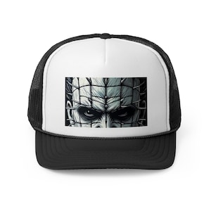 May include: Black and white trucker hat with a graphic of a character's face with a grid-like pattern and pins. The hat has a white front panel with the graphic, a black brim, and a black mesh back.