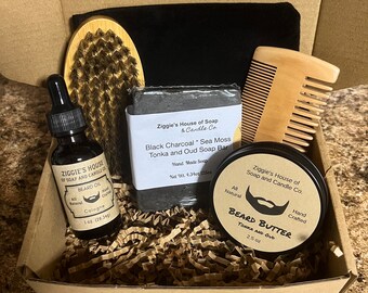 May include: A gift box filled with beard care products, including a black charcoal soap bar, beard oil, beard butter, a wooden comb, and a brush. The box is lined with brown paper shreds. The products are all labeled with the brand name "Ziggie's House of Soap and Candle Co."