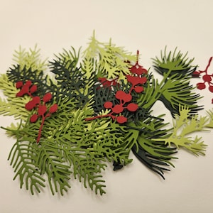 May include: A decorative arrangement of paper cutouts featuring evergreen branches in shades of green and dark green, accented with bright red berries. The design is layered, creating a dimensional effect, perfect for holiday crafts.
