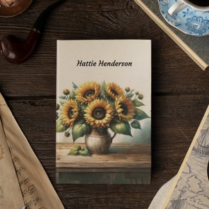 May include: A personalised journal with a floral design featuring a bouquet of sunflowers in a vase. The journal cover has the name "Hattie Henderson" printed on it.