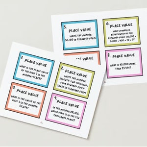 May include: Two white sheets of paper with place value math problems. Each card has a different colored border and contains questions about place value, such as writing numbers in expanded form and identifying digit values.