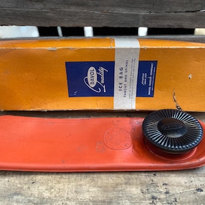 May include: A red rubber ice bag with a black plastic cap. The box reads "Davol Quality Ice Bag Throat and Spinal".
