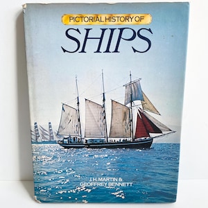 May include: A vintage book titled "Pictorial History of Ships" with a blue cover. The cover features a painting of a tall ship sailing on blue water with white sails and red accents. The book's title is in large, dark blue letters.
