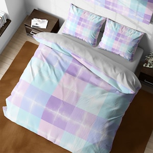 May include: A white duvet cover with a light blue and purple plaid pattern. The duvet cover is on a bed with two matching pillowcases and a decorative pillow with a similar pattern.
