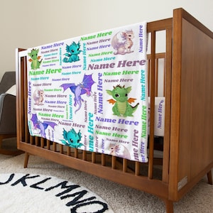 May include: A white baby blanket with a repeating pattern of green and purple dragons. The blanket has the text "Name Here" repeated throughout the design.