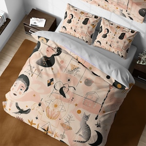 Könnte beinhalten: Ein rosa-weißer Bettbezug mit einem verspielten Muster aus Sternen, Monden, geometrischen Formen und stilisierten Gesichtern. Das Muster enthält auch einen Vogel, eine Katze und ein kleines Haus. Der Bettbezug ist auf einem Bett mit zwei passenden Kissenbezügen zu sehen.