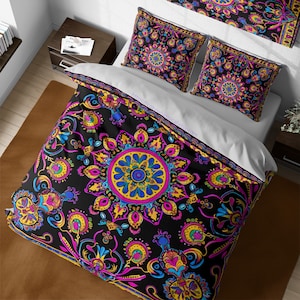 May include: A black duvet cover with a colorful mandala pattern. The duvet cover features a large, intricate mandala in the center, surrounded by smaller mandalas and floral designs. The colors in the pattern include pink, yellow, blue, green, and purple.