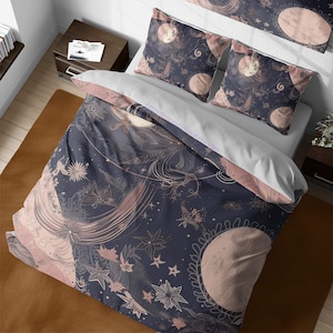 May include: A navy blue duvet cover with a pink and white moon and star pattern. The duvet cover features a whimsical design with delicate floral details and swirling lines. The pattern is reminiscent of a celestial night sky.