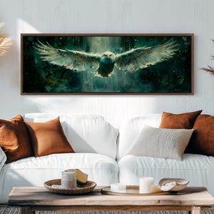 May include: A framed canvas print of a white eagle in flight against a dark green and blue background. The eagle is flying towards the viewer with its wings spread wide. The background is blurred and has a watercolor effect.