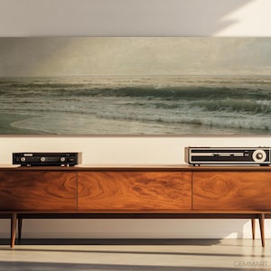 May include: A vintage-style wooden entertainment center with a black stereo receiver and a framed seascape painting above it.