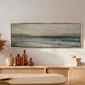 May include: A framed seascape painting with a muted color palette depicting a stormy ocean with waves crashing against the shore. The painting is displayed on a light wood shelf with decorative vases and bottles.