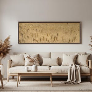 Puede incluir: Un dise&ntilde;o de interior de sala de estar con un sof&aacute; beige, dos almohadas beige, una manta beige, una mesa de caf&eacute; de madera, una silla de madera, dos plantas de hierba de la pampa secas, una obra de arte de pared enmarcada en oro con un dise&ntilde;o abstracto beige, una l&aacute;mpara colgante con una pantalla beige y una mesa auxiliar de madera con un otomano beige.