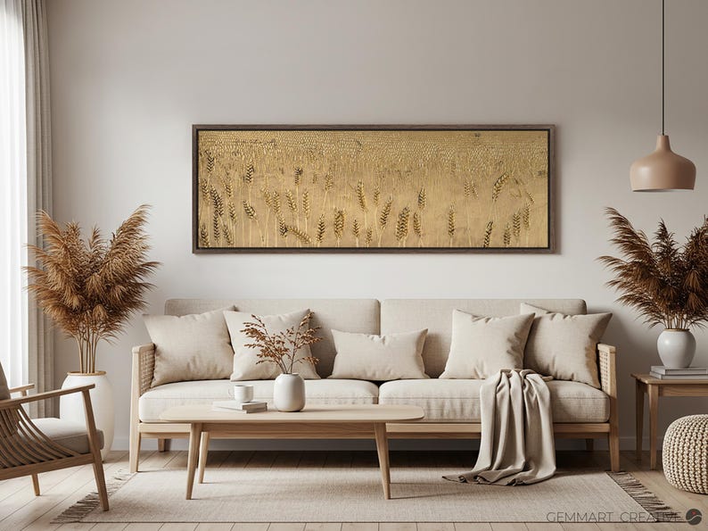Puede incluir: Un dise&ntilde;o de interior de sala de estar con un sof&aacute; beige, dos almohadas beige, una manta beige, una mesa de caf&eacute; de madera, una silla de madera, dos plantas de hierba de la pampa secas, una obra de arte de pared enmarcada en oro con un dise&ntilde;o abstracto beige, una l&aacute;mpara colgante con una pantalla beige y una mesa auxiliar de madera con un otomano beige.