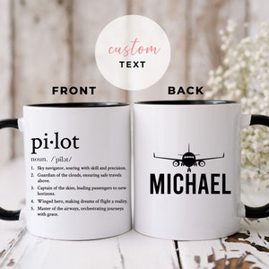 May include: White ceramic mug with a black rim and handle. The front of the mug has the word "pi-lot" defined as a noun with five bullet points describing the role of a pilot. The back of the mug has a black silhouette of an airplane and the name "MICHAEL" printed below.