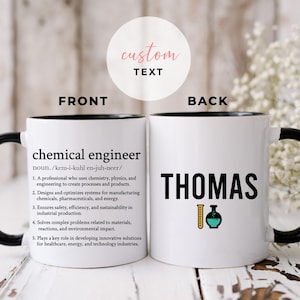 Könnte beinhalten: Weiße Keramiktasse mit schwarzem Rand und Henkel. Die Vorderseite der Tasse zeigt die Definition eines Chemieingenieurs. Die Rückseite der Tasse trägt den Namen "THOMAS" und eine Grafik mit einem Becherglas und einem Reagenzglas.