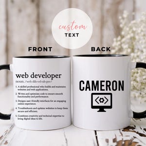 以下が含まれることがあります： 黒色の縁取りと持ち手を持つ白いセラミック製のマグカップ。マグカップの前面には、「ウェブ開発者」の定義が黒色のテキストで印刷されています。マグカップの背面には、黒色のテキストで「CAMERON」という名前と、コードシンボルが表示されたコンピューター画面の白黒のアイコンが印刷されています。
