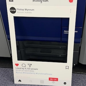 May include: White photo booth frame with a black and white Instagram logo at the top. The frame has a cutout for a person's face. The text "Fitstop Wynnum" is below the logo, followed by "Wynnum, Australia". The bottom of the frame has a white Instagram post with a red heart, a speech bubble, a paper airplane, and a bookmark icon. The text "Liked by 4,122 people" is above the text "STOP AT NOTHING". The hashtags "#joinus #fitnessfamily #functionalfitness" are below the text. The text "Show all comments" is below the hashtags. A red heart icon with the text "4,122" is in the bottom right corner of the post.