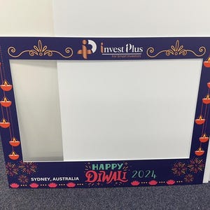 May include: A blue and white photo booth frame with a cutout for a person's head. The frame is decorated with red and orange diya lights and fireworks. The text "Happy Diwali 2024" is printed on the bottom of the frame. The text "Sydney, Australia" is printed on the bottom left corner of the frame. The text "Invest Plus For Smart Investors" is printed on the top of the frame.