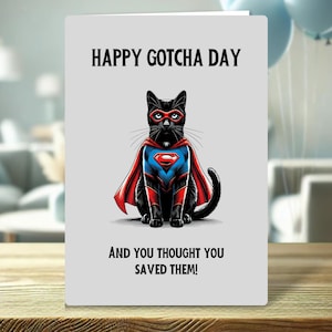 May include: Greeting card featuring a black cat dressed as a superhero. The cat has a red mask and cape, and a blue and red suit. Text reads "HAPPY GOTCHA DAY" and "AND YOU THOUGHT YOU SAVED THEM!"