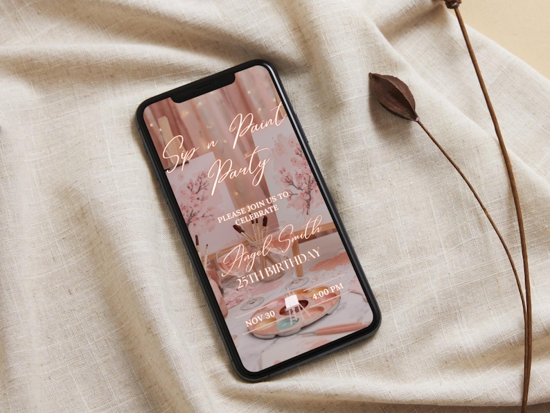 May include: A smartphone displays a digital invitation for a "Sip n' Paint Party" with the text "Please join us to celebrate Angel Smith 25th Birthday" on a pink and white background. The phone rests on a beige fabric.
