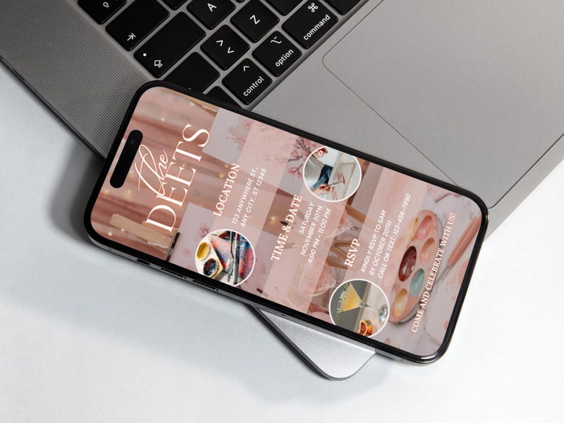 May include: A smartphone displays an event invitation with a pink and white marble design. The invitation includes the text "The DEETS", location, time, date, and RSVP information. The phone rests on a laptop.