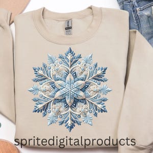 May include: Beige crewneck sweatshirt featuring a detailed, symmetrical snowflake design in shades of blue and white. The snowflake has intricate patterns and a three-dimensional appearance. The text "spritedigitalproducts" is at the bottom.