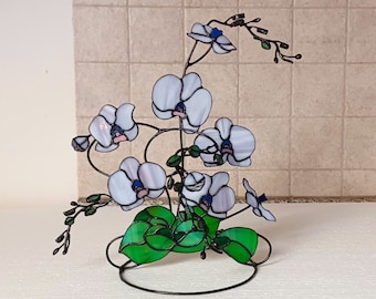 Glasorchidee, hellviolette Blüte mit grünen Pflanzenblättern auf einem Metallständer, Blumenskulptur, besteht aus mehreren Zweigen, 3D