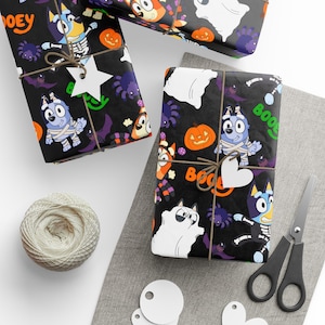 Può includere: Carta da regalo a tema Halloween con personaggi dei cartoni animati, zucche, ragni e la parola "BOO" su sfondo nero. I regali sono legati con spago e adornati con etichette bianche. Sono visibili anche un gomitolo di spago e delle forbici.