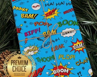 May include: A wrapped gift with blue comic book-style wrapping paper. The paper features action words like "BAM!" and "ZAP!" in yellow, red, and white speech bubbles. The gift is tied with twine and has a gold "Premium Choice" seal.