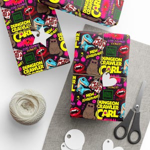 May include: Wrapping paper featuring a repeating pattern of Dungeon Crawler Carl text, blue dinosaurs, brown cats with sunglasses, red lips with fangs, and text reading God Damn Donut and New Achievement, tied with twine and white star or heart tags.