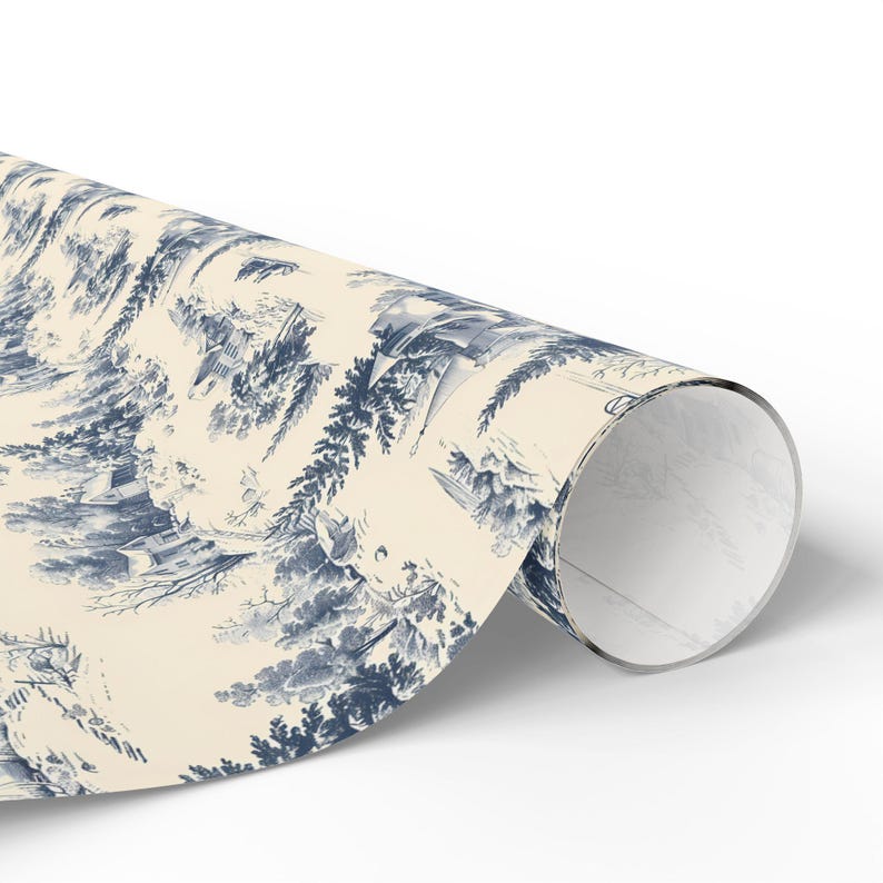 A single roll of wrapping paper printed with a blue and white winter village pattern rests on a white background.