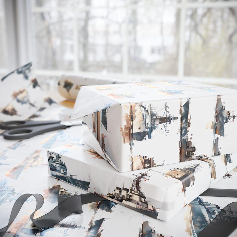Two wrapped gift boxes featuring a battleship watercolor pattern resting on a surface with a blurred window background, scissors, and a black ribbon.
