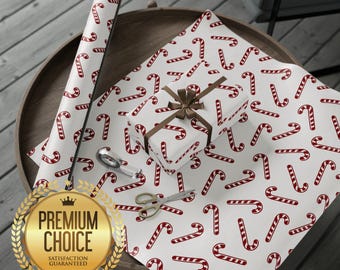 May include: White wrapping paper with a red candy cane pattern, a wrapped gift with a brown bow, and a roll of matching paper. Scissors and tape are also visible. The scene is set on a wooden table, perfect for Christmas gift wrapping.