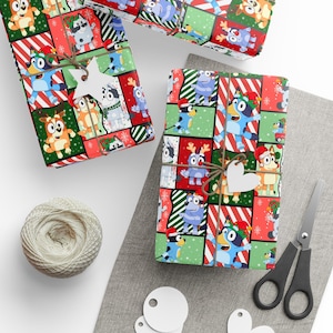 May include: Three wrapped gifts with colorful patterned paper featuring cartoon characters in Christmas attire. The gifts are tied with twine and adorned with star and heart-shaped tags. A ball of twine, scissors, and blank tags are also present.