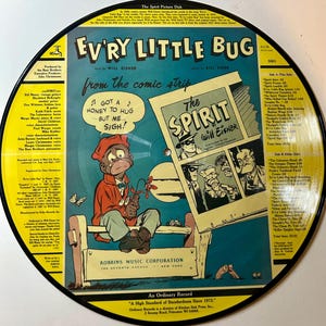 Puede incluir: Un disco de vinilo vintage titulado "Ev'ry Little Bug" de la tira cómica "The Spirit" de Will Eisner. El disco presenta una ilustración de dibujos animados de un personaje con el texto "Got a honey to hug... but me... sigh!" y un panel de cómic.