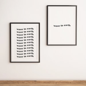 May include: Two framed art prints with black frames and white backgrounds. The left print repeats the phrase "wave to earth". The right print displays the same phrase once.
