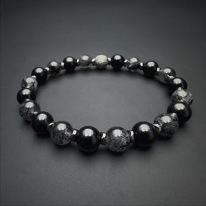 May include: Black beaded bracelet with silver accents. The bracelet features black onyx and black tourmaline beads.