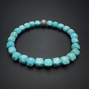 May include: A turquoise gemstone bracelet with a silver clasp. The bracelet is made of faceted beads and is a light blue color.
