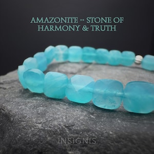 Op de afbeelding: Een armband met facetgeslepen, lichtblauwe amazoniet kralen. De kralen zijn geregen met een zilveren sluiting. De afbeelding bevat de tekst "Amazoniet - Steen van Harmonie & Waarheid" en de merknaam "INSIGNIS".