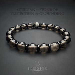 May include: A beaded bracelet featuring smoky quartz and black onyx beads. The bracelet includes a silver accent bead and is displayed on a dark background. Text on the image reads "Obsidian - Stone of Protection & Grounding."