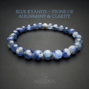 Könnte beinhalten: Ein Armband aus blauen Kyanit-Perlen mit einer silbernen Perle. Die runden, durchscheinenden blauen Perlen sind aufgereiht. Der Text oben lautet "BLUE KYANITE - STONE OF ALIGNMENT & CLARITY". Der Markenname "INSIGNIS" steht unten.