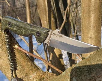 May include: A green and black patterned folding knife with a silver blade and a bottle opener. The knife has the text "TEUTON" and "BOULDER, CO 80303" on the blade.