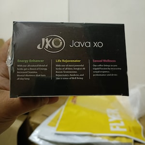 May include: A black box with the text "JXO Java xo" and descriptions for "Energy Enhancer", "Life Rejuvenator", and "Sexual Wellness". The box is held by a person.
