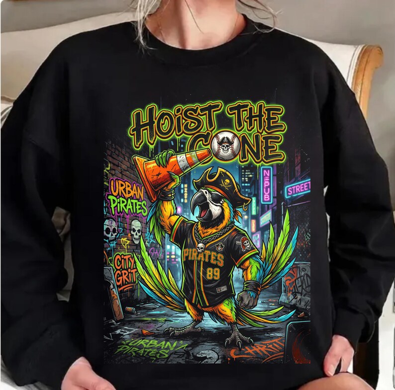 K&ouml;nnte beinhalten: Schwarzes Sweatshirt mit einem farbenfrohen Papageien-Motiv. Der Papagei tr&auml;gt einen Piratenhut und ein Trikot mit der Aufschrift "Pirates 89" und h&auml;lt einen orangefarbenen Verkehrskegel. Der Text lautet "Hoist the Cone" und "Urban Pirates".